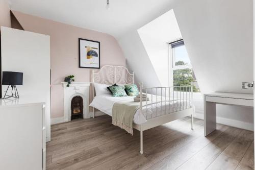 ein weißes Schlafzimmer mit einem Bett und einem Kamin in der Unterkunft Cosy 3 Bed Flat 15mins to Kings Cross in London
