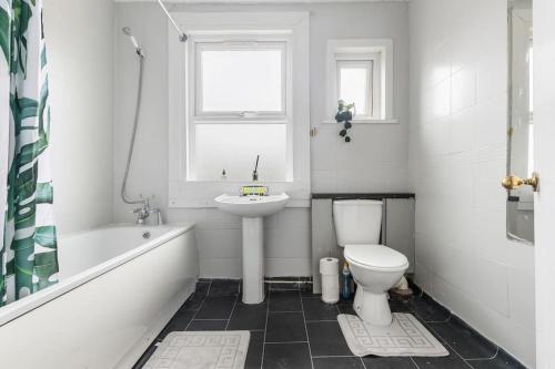 a bathroom with a sink and a toilet and a bath tub at Cosy 3 Bed Flat 15mins to Kings Cross in London