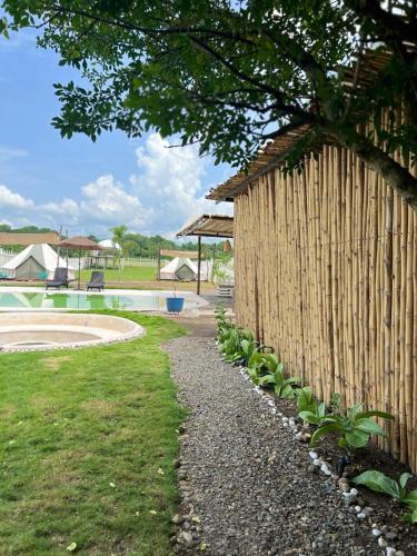 una valla de madera junto a una piscina con un árbol en Dharma Glamping, en Tapachula