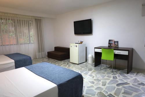 a hotel room with two beds and a desk and a television at Babilla Suites in Cali