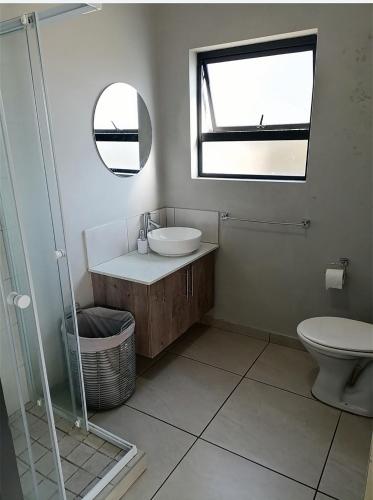 baño con lavabo y aseo y ventana en Alakhe en Randfontein