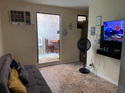 a living room with a couch and a flat screen tv at Hospedagem Recreio dos Bandeirantes in Rio de Janeiro