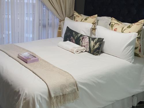un letto bianco con cuscini e una scatola sopra di URlyfstyle Cottage Near Mall of Africa a Midrand