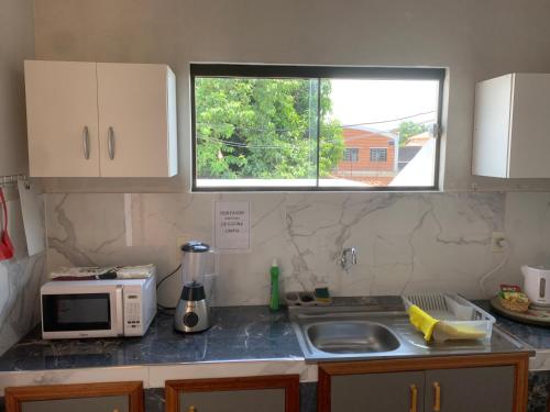 a kitchen with a sink and a microwave and a window at Amplio Departamento 3 habitaciones, excelente ubicación in Asuncion