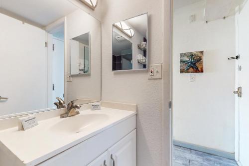Baño blanco con lavabo y espejo en Harbour Beach Resort 618, en Daytona Beach