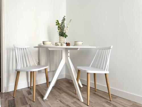 une table avec deux chaises et une table blanche avec une plante dans l'établissement Logement Entier au Centre Ville, à Évreux