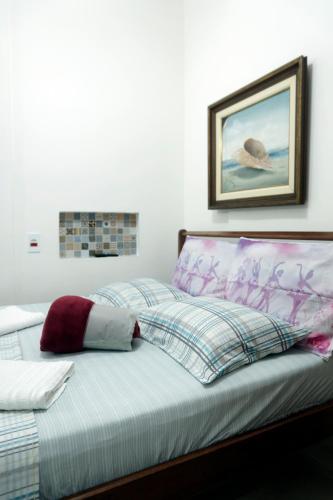 a bed with a pillow and a picture on the wall at CANTO DA ARVORE 1 in Arraial do Cabo