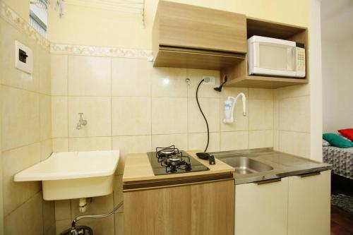 a small kitchen with a sink and a microwave at Apto Centro Histórico ótima localização e iluminado in Porto Alegre