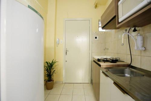 a small kitchen with a sink and a door at Apto Centro Histórico ótima localização e iluminado in Porto Alegre
