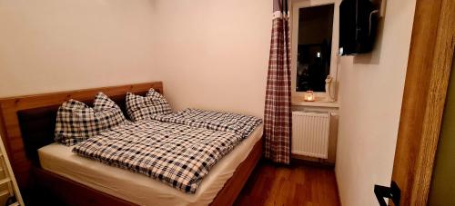 Dormitorio pequeño con cama con manta a cuadros en Apartmán Mumlava en Harrachov