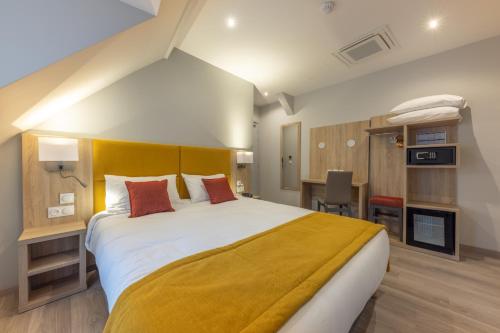a bedroom with a large bed with a yellow blanket at Hotel Saint Augustin in Strasbourg