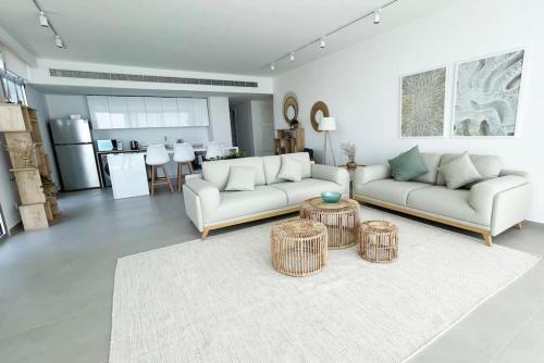 Sala de estar con 2 sofás blancos y 2 mesas en Amchit Bay Beach Residences 3BR w Indoor Jacuzzi en Jbeil