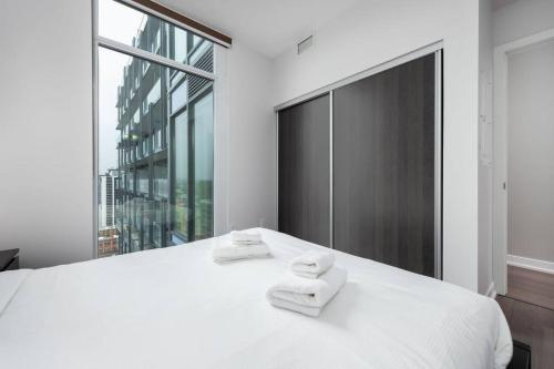 ein Schlafzimmer mit einem weißen Bett mit zwei Handtüchern darauf in der Unterkunft Toronto Condo with a View, St. Lawrence Market in Toronto