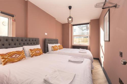 two beds in a room with pink walls at Ettie and Gigi's in Blackpool