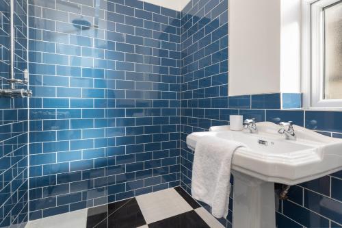 a blue tiled bathroom with a sink and a mirror at Ettie and Gigi's in Blackpool
