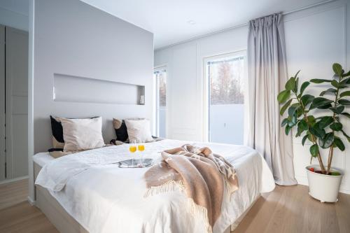 1 dormitorio con 1 cama blanca grande y planta en Rovaniemi, Luxury house near Santa Claus Village with hot tub, en Rovaniemi