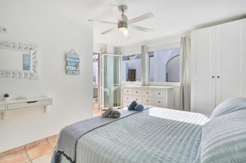 a white bedroom with a bed and a ceiling fan at SunsetView apartment El Cotillo 2-4 personas in Cotillo