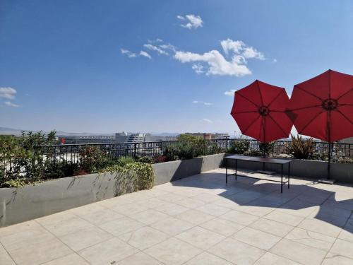 two red umbrellas and a bench on a roof at Zemilo Hotel Apartment in Addis Ababa