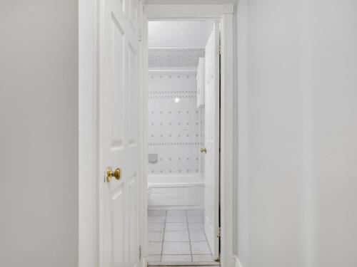 a white bathroom with a tub and a white door at Cozy Home In Downtown Toronto! in Toronto