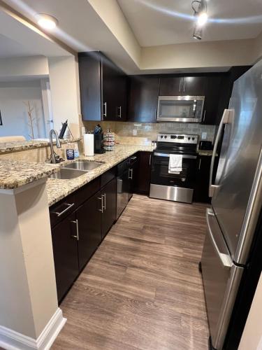a kitchen with black cabinets and a stainless steel refrigerator at Spacious 2 Bed, 2 Bath Uptown Gem in the Heart of the City-Parking-Wi-Fi-Balcony-Walk to BOA Stadium in Charlotte