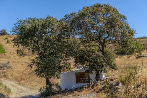 a building under two trees on a hill at Monte Do Malhao - Art, Eco & Spa in Castro Marim