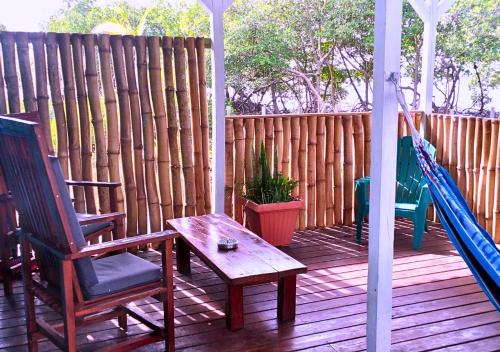 eine Veranda mit 2 Stühlen, einem Tisch und einer Schaukel in der Unterkunft Coco Key EcoLodge - Breakfast - Sea in Bocas del Toro