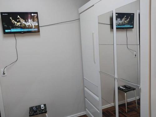 Habitación con espejo y TV en la pared. en AP Novo, Cama Queen Size Nova no Centro de Blu, en Blumenau