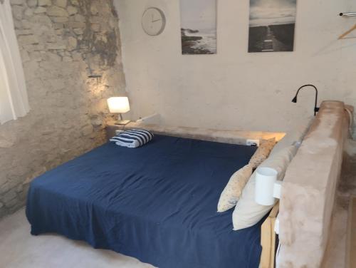 ein Schlafzimmer mit einem blauen Bett und einer Steinmauer in der Unterkunft Can Polta in Santa Margalida
