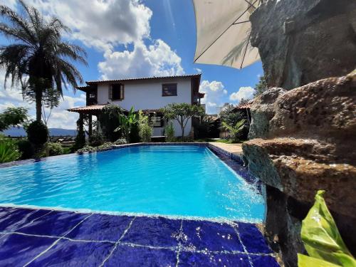 a swimming pool with an umbrella in front of a house at Pousada Residência Balestra in Tiradentes