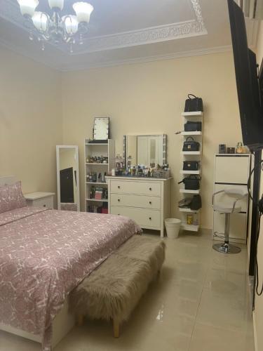a bedroom with a bed and a dresser and a television at One bedroom apartment in Jimi in Al Ain