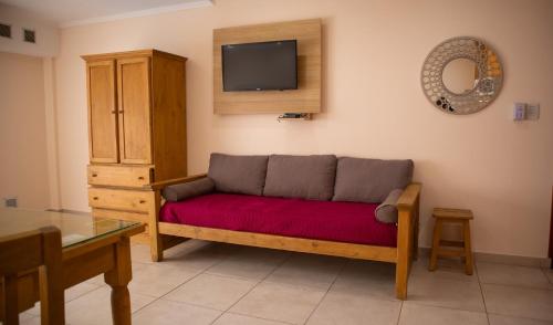 a living room with a couch and a tv at Departamentos Sol y Arena in San Clemente del Tuyú
