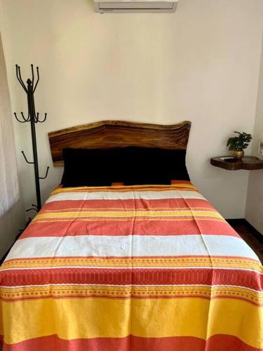 Casa Guiba 3 Puerto Escondido في بويرتو إسكونديدو: غرفة نوم مع سرير مع بطانية ملونة عليه