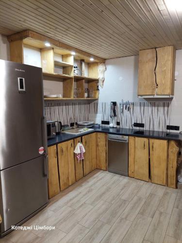 a kitchen with a stainless steel refrigerator and wooden cabinets at Котеджі Цімбори in Yablunytsya
