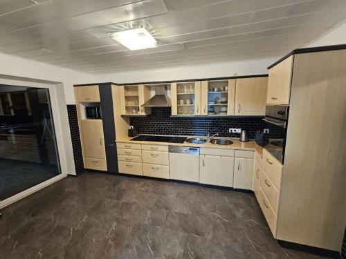 a large kitchen with white cabinets and a sink at Haus an der Weser Ferienwohnung in Brevörde