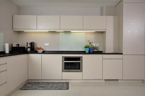 una cocina blanca con armarios y electrodomésticos blancos en Captain's Lounge - Bungalow XL en Westerland