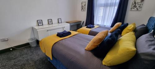 two beds in a room with yellow and blue at Sunrise at The Dens, 3 Rooms, 4 Beds, 2 Bathrooms, Fully Equipped, Wifi, Parking, Contractors Accommodation, Trade Favourite, Long Stays Rates Available by Sunrise Short Lets Dundee in Dundee