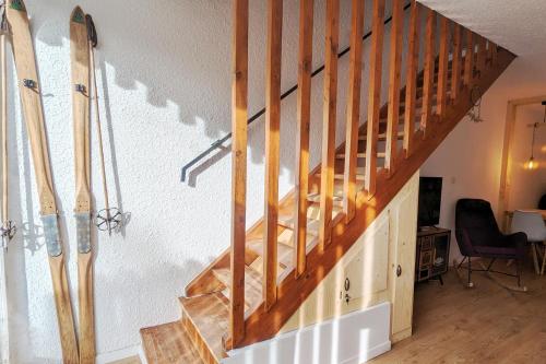 un escalier en bois avec des planches de surf penchées contre un mur dans l'établissement L’ALPIN AU PIED DES PISTES ET COMMERCES, à Saint-Chaffrey