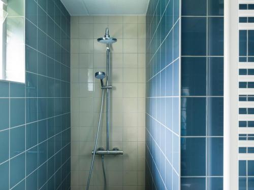 prysznic w łazience wyłożonej niebieskimi kafelkami w obiekcie Amazing holiday home in Friesland with Sauna and outdoor Spa w mieście Earnewâld