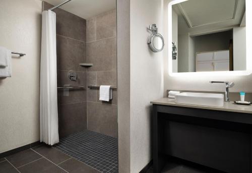 a bathroom with a shower and a sink and a mirror at The Union Station Nashville Yards, Autograph Collection in Nashville