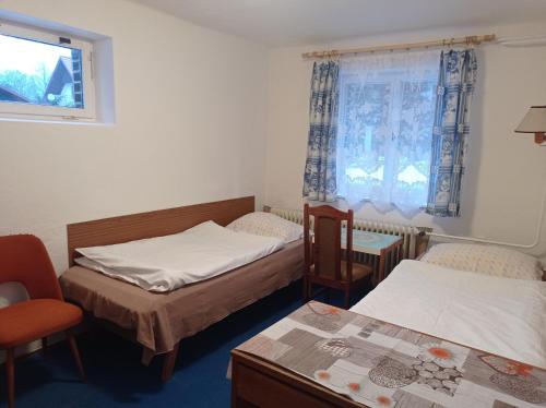 um quarto com duas camas e uma cadeira e uma janela em Ubytování u Boženky em Destné v Orlických horách