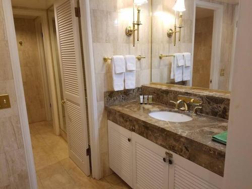 a bathroom with a sink and a large mirror at Brooks Beach Vacations 4 star Wyndham Resort 2003 Waikiki in Honolulu