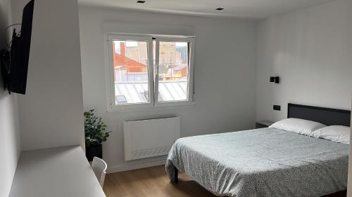 a white bedroom with a bed and a window at Bierzo Habita Apartments in Ponferrada