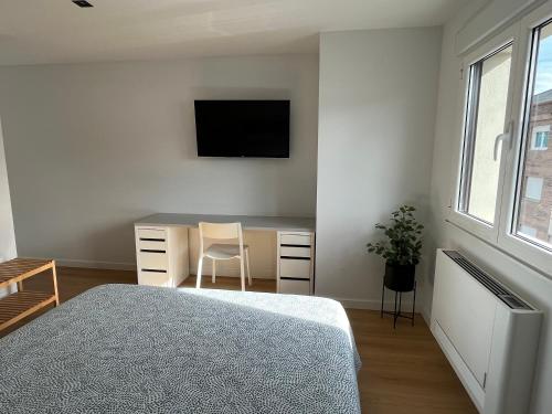 1 dormitorio con escritorio y TV en la pared en Bierzo Habita Apartments, en Ponferrada