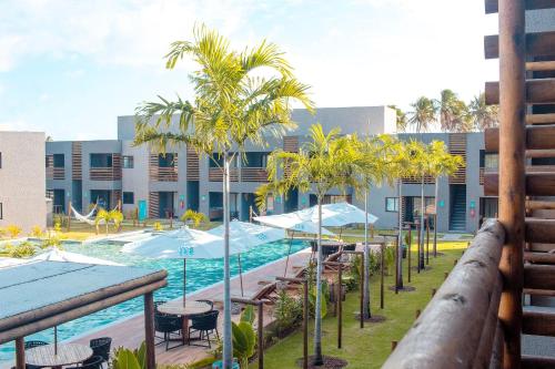 une piscine avec des palmiers et des chaises et un complexe dans l'établissement Excelente condomínio com uma belíssima área de lazer próximo à praia do Patacho, à Porto de Pedras