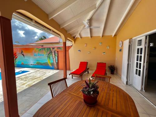 un patio con tavolo in legno e sedie rosse di Louer la Villa Turquoise Avec Piscine Privée a Baie-Mahault