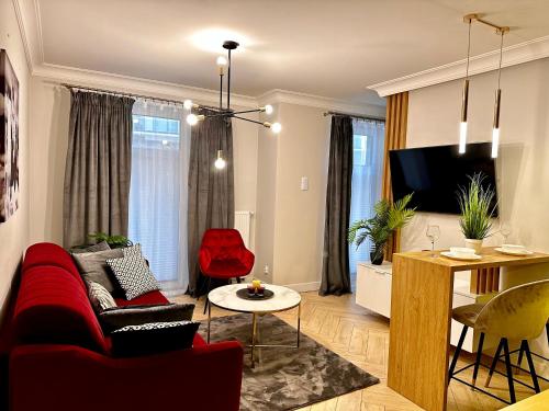 a living room with a red couch and a table at Apartamenty Kielce- APARTAMENT RUBIN przy zalew kielecki, faktura, parking, centrum in Kielce