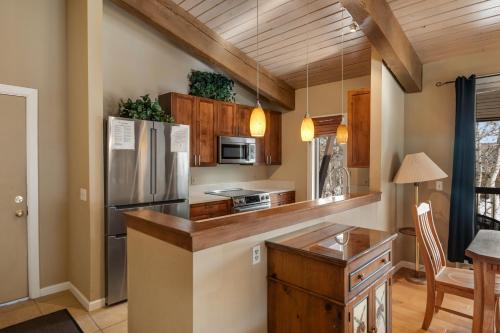 a kitchen with wooden cabinets and a stainless steel refrigerator at Woodbridge Condo by Snowmass Vacations in Snowmass Village