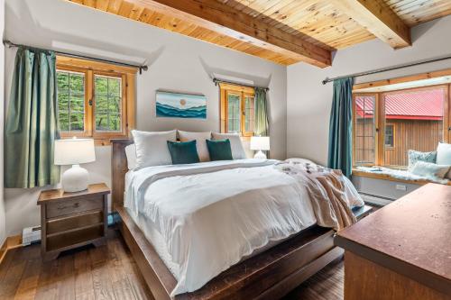 a bedroom with a large bed and windows at Beautiful Log Cabin! Hot-Tub, Bonfire & Private Yet 4 Mins to Downtown! in Ellicottville