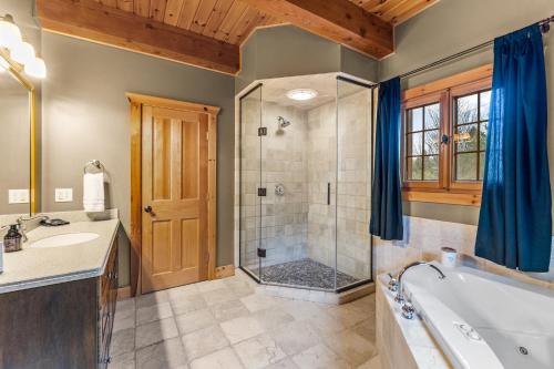 a bathroom with a tub and a sink and a shower at Beautiful Log Cabin! Hot-Tub, Bonfire & Private Yet 4 Mins to Downtown! in Ellicottville