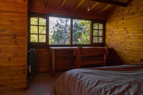 a bedroom in a log cabin with a bed and windows at Espacio Aquarel Patagonia in Los Repollos